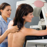 Patient having breast scan in hospital, nurse assisting, side view